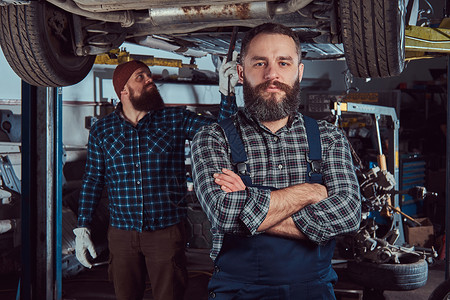 两个留胡子的野蛮机械师在车库修理一辆电梯图片