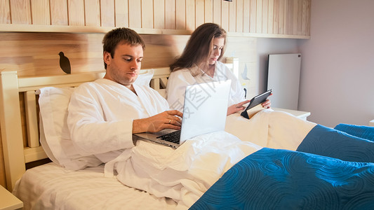 在床上躺着的夫妇在笔记本电脑和平图片