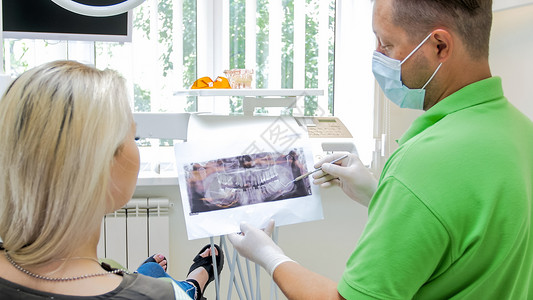 向病人解释牙齿X光照片的牙科医图片