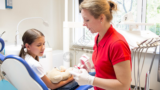 儿科牙医向她的病人展示人造下巴图片
