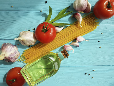 蓝色木质背景中的意大利面干番茄大蒜胡椒油图片