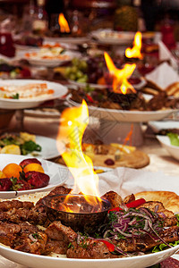 装饰豪华的餐桌盘子中间有烤肉和火图片