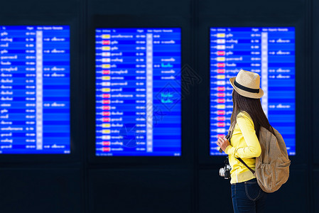 年轻女子在国际机场看着航班信息板图片