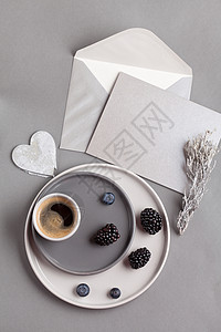 咖啡杯的顶视图和带信封的灰色明信片背景图片