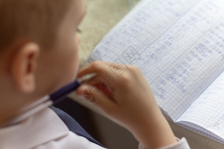 家庭教育男孩手用笔在传统的白色记事本纸上手写英文单词男孩给朋友写了一封信放学背景图片