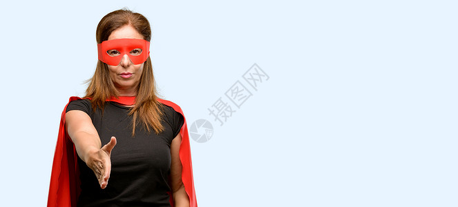 身戴红色面具和披斗篷的中年超级英雄妇女举起手来欢迎握手装扮图片