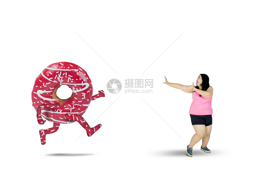 健食概念胖女人在工作室跑时被美味甜圈图片