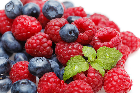 天然蓝莓和有薄荷叶的草莓白色背景上隔图片