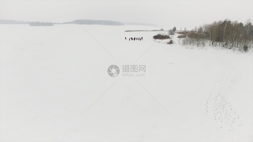 一群徒步旅行者在森林里的雪路上录像一群游客和狗在冬天的森图片
