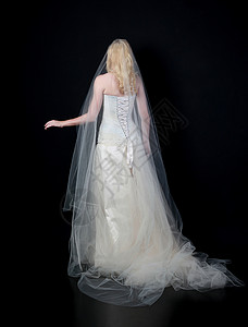 身穿白新娘礼服的模特儿全长肖像站在黑色背景图片