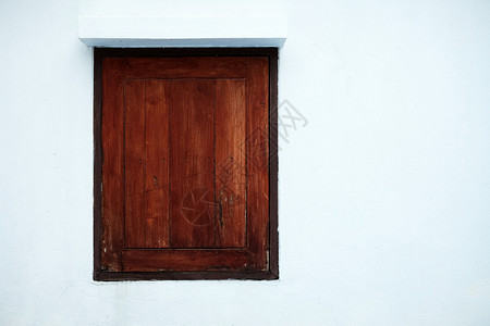 白色混凝土墙背景上的旧木窗图片