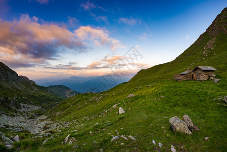 日落在阿尔卑斯山草地和草原上有山林小屋避难所图片