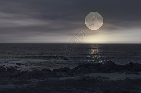 海平面上充满浪漫的满月在一个阴云的夜晚从图片