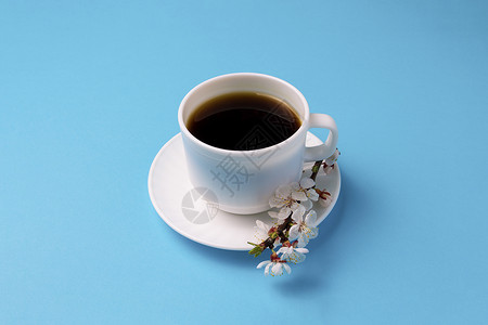 白杯与咖啡和樱花小分会在蓝色背景上最微小的风格图片