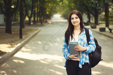 带着背包和笔记本站在公园暑假教育校园和青少年概念中的快乐年轻可爱微图片