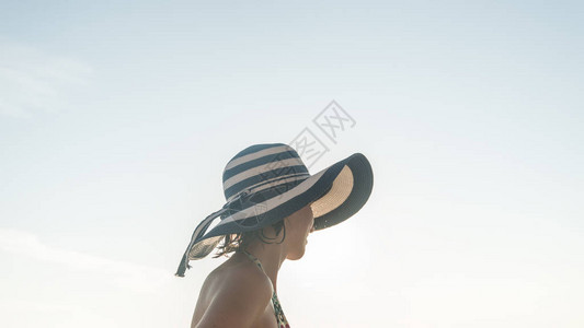穿泳衣的女人戴着蓝草帽在阳光图片