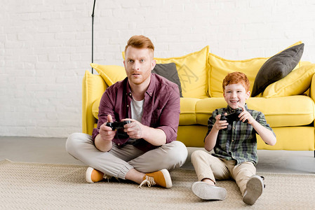 快乐的父亲和儿子坐在地毯上在家图片