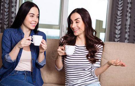 闲话半盏茶两个微笑着的美女在家里喝咖啡或茶背景