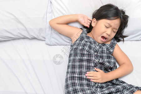 患有胃痛和躺在床上的亚洲儿童图片