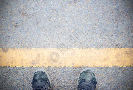 男脚和旧黑鞋站在混凝土地板或街道沥青路面上图片