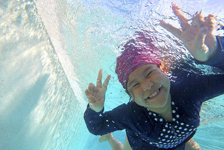 快乐的小女孩在游泳池的水下玩耍图片