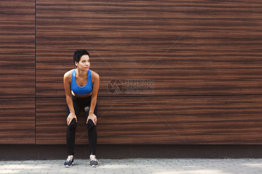 疲劳的跑步者呼吸奔跑休息靠在木墙上手膝跪着的运动员女在锻炼后休息时精疲力图片