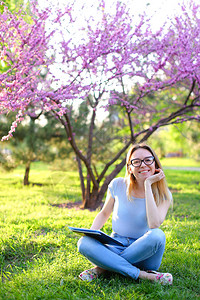 女学生坐在绿色草地上图片