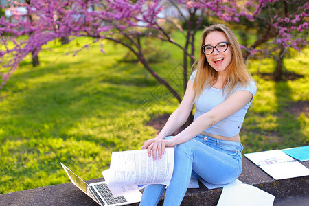 成功的女学生在春天公园用笔记本电脑和论文学习教育和户图片