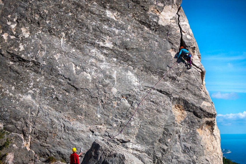 头盔的登山者一个女人爬上岩石朋友们在大自然中从事极限运动攀登的保险和安全一个男图片