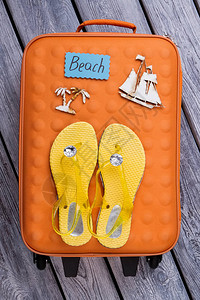 沙滩上的东西平铺的橙色手提箱和图片