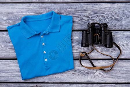 蓝色马球T衬衫和望远镜木质背景图片