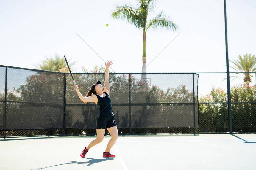 年轻的有史帕密的女网球运动员站在基线上抛球并准图片