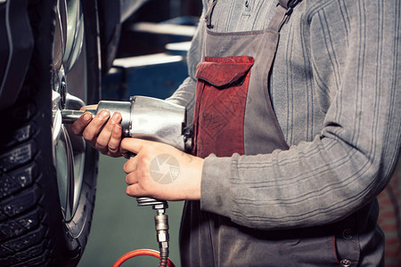 男修车机工轮胎和扳手在修图片