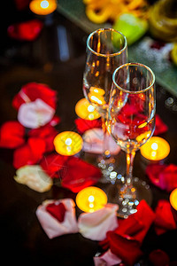 特写两杯香槟蜡烛和玫瑰花瓣图片