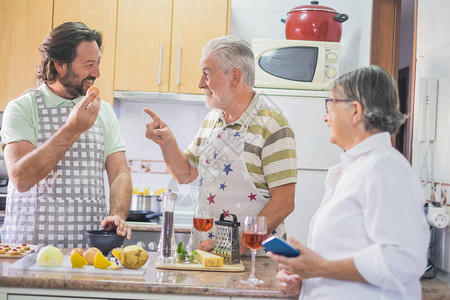 家庭烹饪的室内厨房场景父亲母亲和儿子老年夫妇和中年男开玩笑和图片