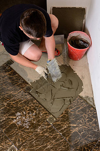 师傅在水泥表面用胶水溶液铺盖大理石砖时推着一个有胶图片