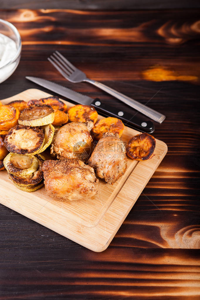 木桌上的炸鸡肉和烤蔬菜图片
