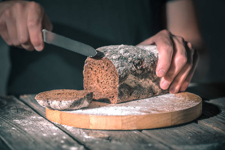面包师在美丽的木背景健康食品的概念和面包业上切新鲜面包图片