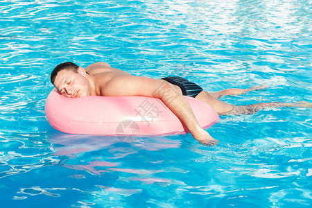 酒鬼在泳池里游着粉红色圆圈喝醉的家图片
