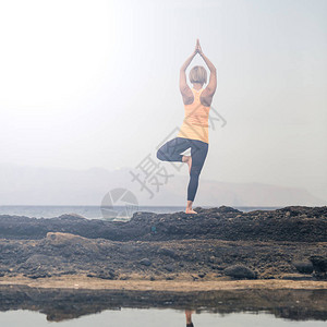 在瑜伽姿势海景海滩和岩石中冥想的女人图片