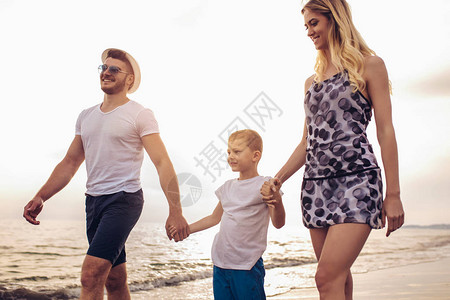 母亲和父亲在宁静的海滩上与儿子一起走来去图片