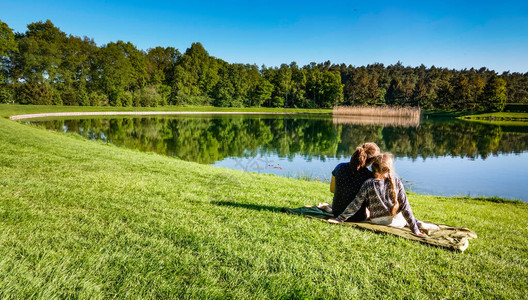 两个年轻的女孩坐在湖边钓鱼在一个阳光明媚的午后图片