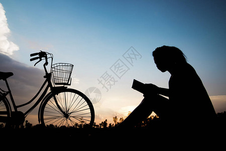 剪影妇女在阳光下骑自行车看书图片