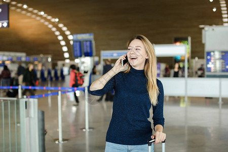 女peson在机场大厅用手提袋用smarphone说话现代技术和国图片
