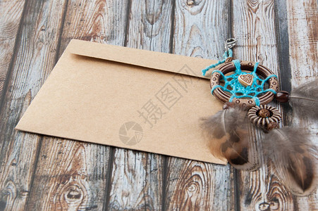 手工制作的蓝色棕梦想捕捉器和木质背景的Kraft信封图片