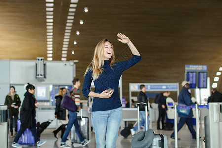 女手持智能手机手提箱和举手站在机场大厅旅行现代小工具和积图片