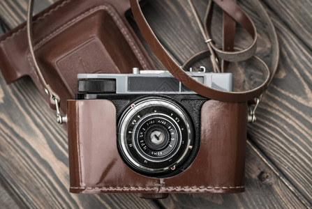木板背景下棕色皮套中的旧胶卷相机背景图片