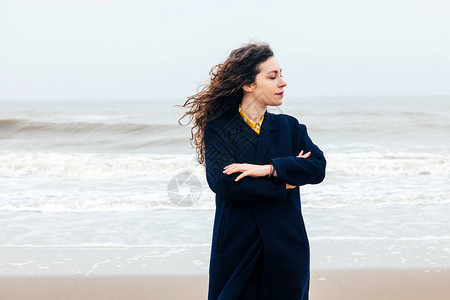 一个长的卷发女孩在寒冷的冬海中的特写镜头海上强风雨中图片