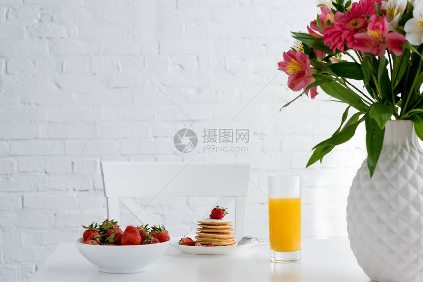 美味的煎饼鲜草莓和橙汁放在桌上白图片