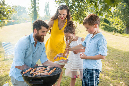 献身父亲帮助儿子在夏季家庭野餐期间图片